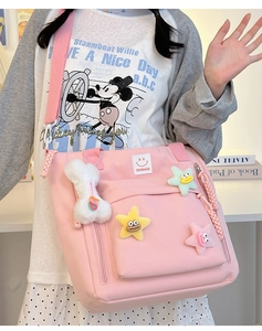Detail of pink nylon shoulder bag featuring star patches and a white plush toy charm