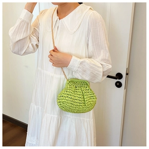 Détail du sac tressé vert citron avec chaîne dorée sur une robe blanche