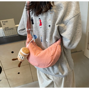 Detail of pink crescent fabric crossbody bag with cute plush charm on a casual model