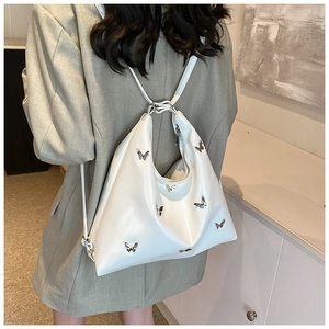 Dettaglio della borsa hobo in pelle PU bianca con farfalle metalliche 3D indossata dal modello