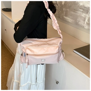 Close-up of pink nylon crossbody bag with ruffled strap and cute bear embroidery