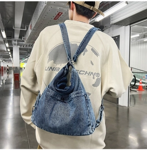 Close-up of washed blue denim backpack fabric texture and adjustable metal buckle straps
