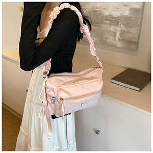 Detail of pink nylon shoulder bag with cute bear badge and ruffled strap on casual model