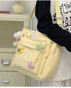 Close-up of pale yellow nylon shoulder bag with cute 3D star charms and adjustable strap