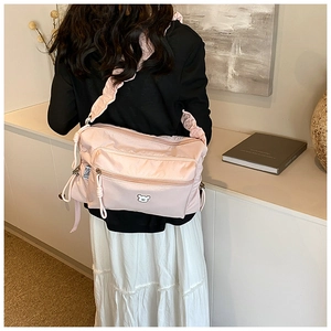 Detailed close-up of light pink nylon crossbody bag featuring a cute white bear embroidery