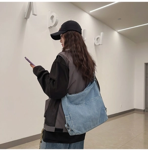 Casual light blue denim crossbody bag shown on model in a modern white hallway setting