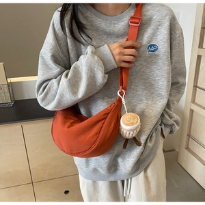 Detail of orange nylon crossbody bag with adjustable strap and plush coffee cup charm