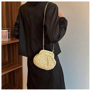 Vue détaillée d'un sac nuage en paille beige avec chaîne dorée portée par un mannequin