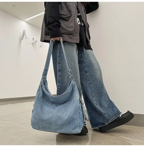 Detail of light blue washed denim shoulder bag featuring side pockets and adjustable strap