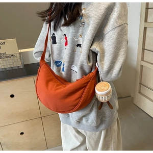 Detail of an orange crescent crossbody bag with a cute coffee cup plush charm accessory
