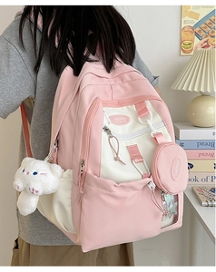 Detailed view of pink and white nylon backpack with cute plush cat and coin purse accessories