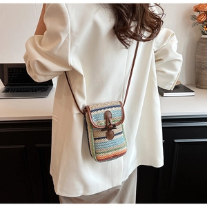 Detailed view of colorful woven straw crossbody bag with brown leather flap and strap