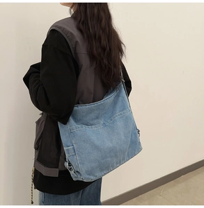 Detail view of large denim shoulder bag with double front pockets and adjustable strap