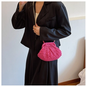 Détail d'un sac en paille tissée rose vif avec une fine bandoulière en chaîne dorée