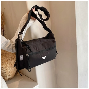 Detail of black nylon crossbody bag featuring a cute bear charm and ruched shoulder strap