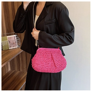 Vue détaillée du sac en paille tressée rose avec chaîne en métal porté par un mannequin