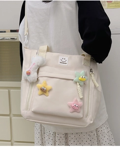 Detail of off-white nylon tote bag with colorful star plush charms and shoulder strap
