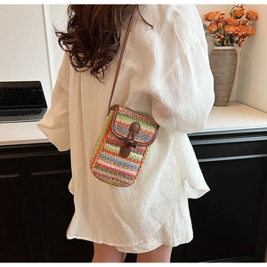 Detail of colorful striped straw crossbody bag with leather trim and horn buckle closure