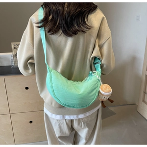 Close-up of mint green crescent crossbody bag with cute plush coffee cup charm