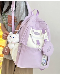 Detail view of lavender and cream nylon backpack featuring a cute cat plush pendant charm