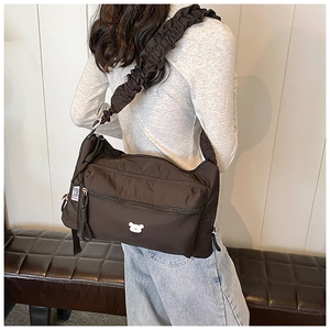 Detail of black nylon pleated shoulder bag with cute bear embroidery and wide strap