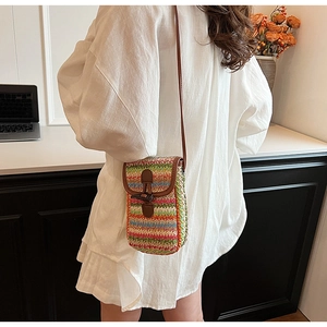 Detail of multi-color woven straw crossbody phone bag with horn buckle and leather strap