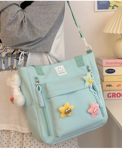 Detail of light blue nylon shoulder bag with smile logo and plush star charms