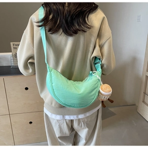 Detail view of mint green crescent bag with cute coffee cup plush charm on shoulder strap