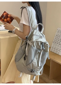 Detail view of light grey nylon backpack with side mesh pockets and adjustable buckles