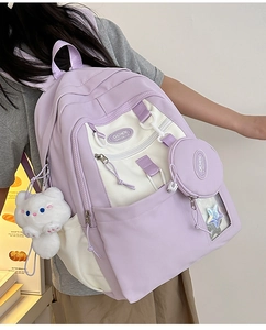 Detail of color-block nylon backpack featuring a cute cat plush charm and mini coin pouch