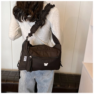 Detail of black nylon crossbody bag with pleated strap and cute bear embroidery on the back