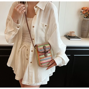 Detail of multi-color striped straw woven crossbody bag with vintage button and slim strap