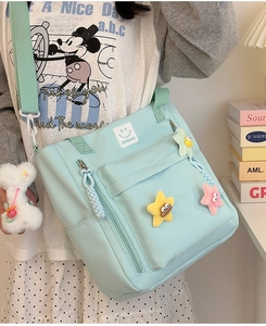 Detail view of mint green nylon bag with cartoon pins and white bone keychain accessory