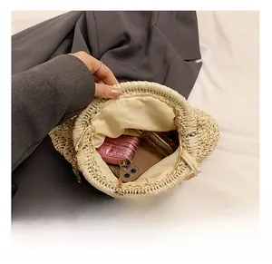 Detail view of woven straw crossbody bag interior showing phone and makeup storage