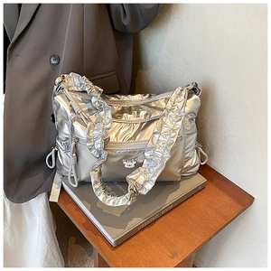 Detail of quilted silver crossbody bag featuring a metal bear logo and ruched strap