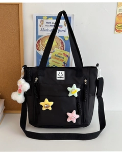 Detail of black nylon tote bag with colorful star pins and a white plush puppy keychain