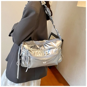 Detail of metallic silver quilted crossbody bag with ruffled strap and bear logo