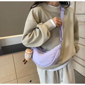 Detail of light purple crescent bag with adjustable strap and cute plush cup charm