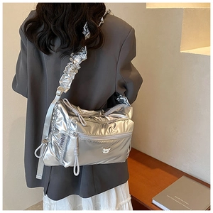 Detail of silver metallic quilted bag featuring ruffled strap and bear logo emblem