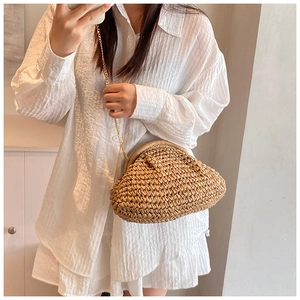 Macro detail of natural straw woven cloud bag with elegant gold chain strap