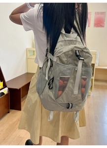 Detail of light grey nylon backpack with functional buckles and breathable side mesh pockets