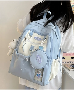 Close-up of light blue nylon backpack featuring a plush bear charm and star sequin window