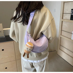 Detail of light purple crescent bag with cute coffee cup plush charm on a nylon strap