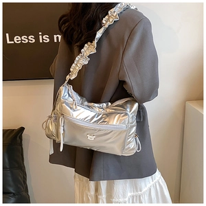 Metallic silver crossbody bag with ruched strap and 3D bear detail in a lifestyle setting