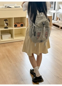 Detail view of a light gray nylon backpack featuring mesh pockets and adjustable buckles