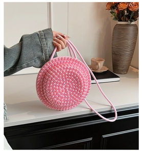 Dettaglio della borsa rotonda di perle iridescenti rosa con manico in corda intrecciata