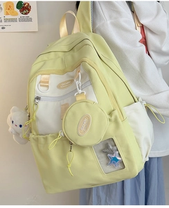 Detail of light yellow nylon backpack featuring a mini pouch and white plush cat charm