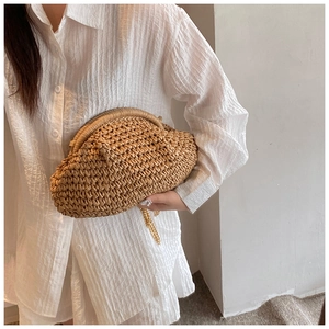 Detail of hand-woven straw cloud clutch bag with gold chain strap for summer vacations