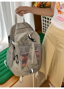 Detail of dark gray nylon backpack featuring mesh side pockets and reflective safety strips