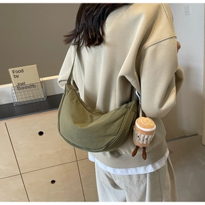 Detailed shot of dark green canvas crescent bag with coffee cup plush pendant charm